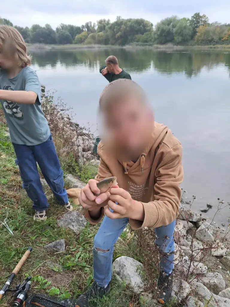 Jungangler zeigt stolz ein gefangenes Rotauge