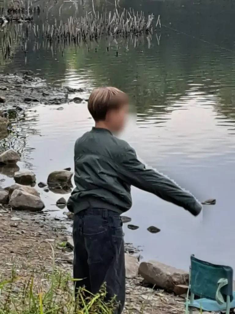 Jungangler steht am Ufer und wirft seine Montage aus